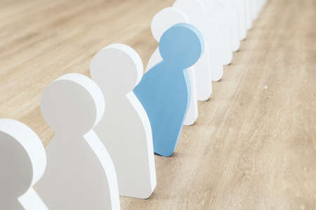 Successful choice and leadership concept with blue human wooden figure falling out of line of white...