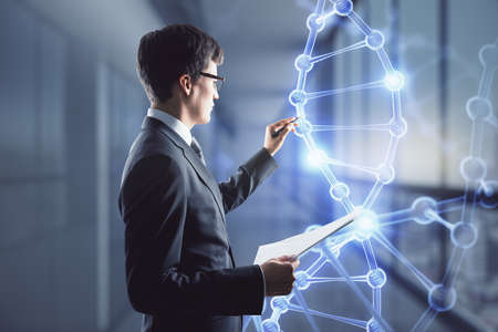 Bioengineering concept with businessman writing on digital touch screen with glowing dna strandの写真素材
