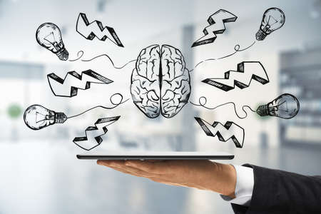 Thinking and brainstorm concept with digital sketch of human brain, light bulbs and lightning strike symbols above digital tablet on businessman handの写真素材