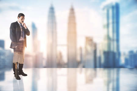 Thinking concept with pensive businessman on glossy floor on city skyscrapers background with copyspace. Mockup, double exposureの写真素材