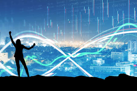 Happy businesswoman standing in front of a cityscape, silhouette, success conceptの写真素材