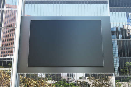 Black empty billboard with dark frame on the wall of modern building with mirror windows. 3D...