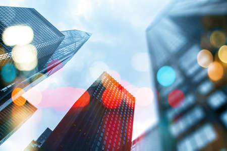 Modern architecture concept with low angle view on city business center buildings with bokeh, double exposureの写真素材