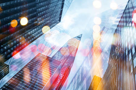 Double exposure of modern office buildings with low angle view and bokeh on abstract city backgroundの写真素材