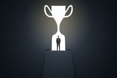 Businessman silhouette in a trophy shaped doorway, dark room, success and leadership conceptの写真素材