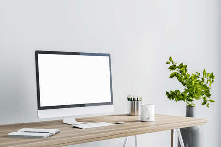 Blank white computer monitor as a part of stylish home work place with modern gray vase on floor at...