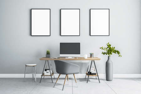 Blank white posters in black picture frame on light wall over stylish work place at home with monitor on wooden table, gray chair and vase on marble floor. 3D rendering, mockupの写真素材