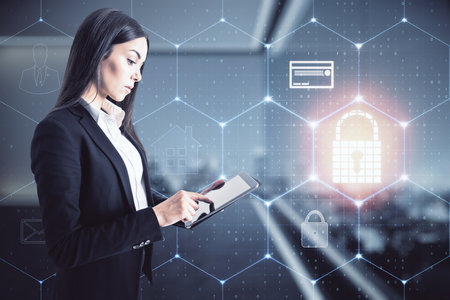 Businesswoman standing with a mobile phone in an office with a keylock hologram, data safety and cybersecurity conceptの写真素材