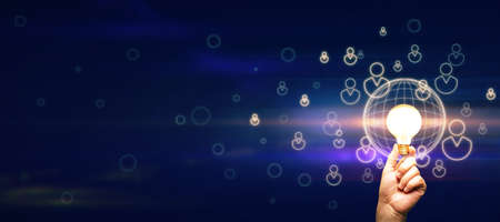 Dark blank background with copyspace and man hand with glowing light bulb surrounded by digital...