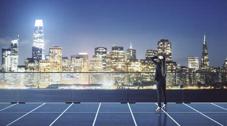 Career growth concept with woman in black suit back view on top of high building balcony and looking...