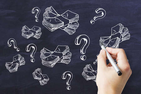 Where to invest concept with man hand writing sketch of wads of money and question marks on...