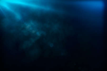 Blurry smoke and blue color ray of light from the top on blank dark background. Mock upの写真素材