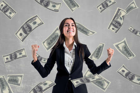 Business success and winner concept with happy businesswoman and chaotically flying dollar billsの写真素材