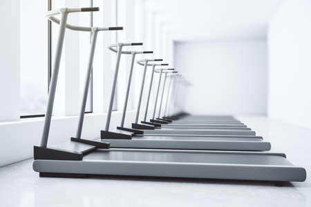 Side view of new gray treadmills in contemporary gym interior with windows, daylight and concrete floor. Fitness club concept. 3D Rendering. High quality photoの写真素材