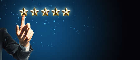 Customer experience concept with businessman hand clicking on golden five star row at abstract dark...