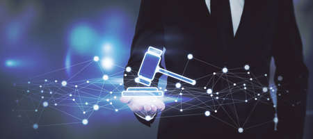 Online auction bidding concept with a man in a black suit showing a digital hammer on the palm of...