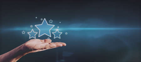 Hand holding glowing stars on blue background with mockup place for your advertisement. Customer...