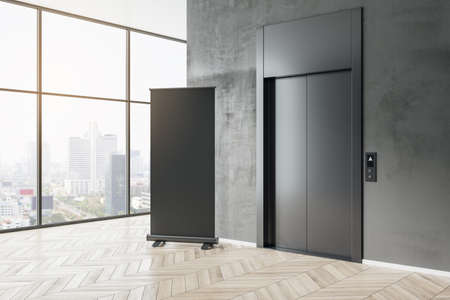 Black poster with copyspace for your text on wooden floor near stylish dark elevator and city view...