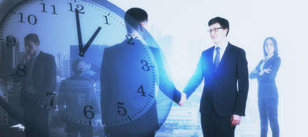 Businesspeople shaking hands on abstract blurry background with clock. Time management and deadline...