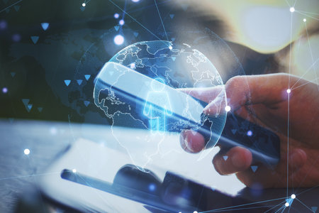 Close up of hand using smartphone with globe and person icon hologram on blurry desktop background. Online recruiting and hiring concept. Double exposureの写真素材
