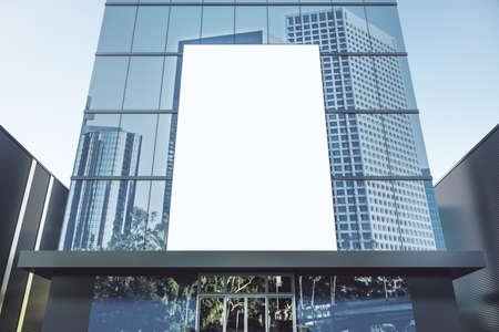 Empty white billboard on shiny glass building exterior with reflections and daylight. Mock up, 3D...