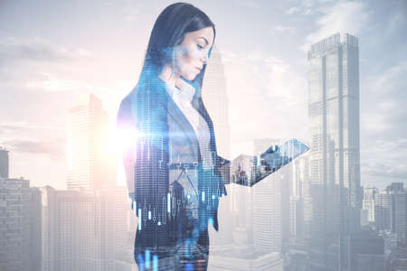 Attractive young european businesswoman using tablet device on abstract bright city background with forex chart and mockup place. Finance, trade and success concept. Double exposureの写真素材