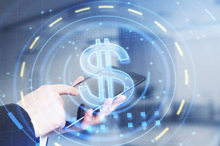 Close up of businessman hand using tablet with glowing dollar sign in blurry office interior....
