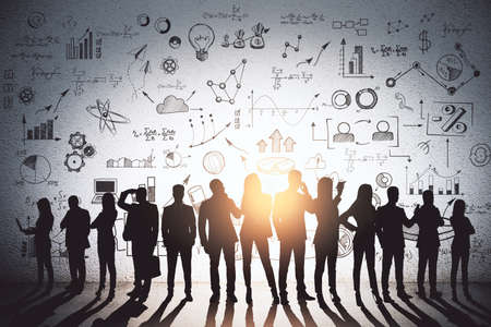 Abstract image of backlit businesspeople standing on concrete wall background with creative business sketch. Teamwork, success, seminar and workshop conceptの写真素材