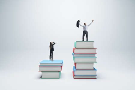 Businessman and woman standing on books on white background. Competition, education, success and knowledge conceptの写真素材