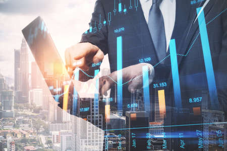 Attractive young european businessmen using laptop together on abstract city background with forex...