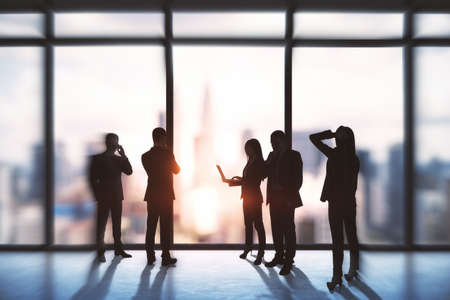 Teamwork and success concept. Group of young businesspeople working together in modern office interior with bright city viewの写真素材