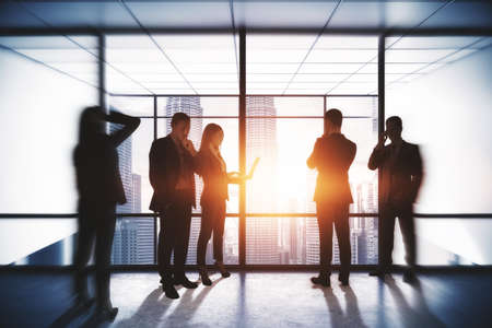 Teamwork and seminar concept. Group of young businesspeople working together in modern office interior with bright city viewの写真素材