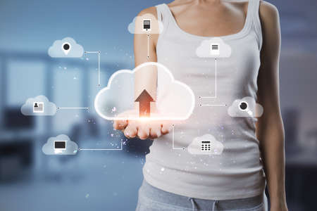 Close up of female hand holding abstract digital cloud on blurry office room background. Cloud computing, database and technology conceptの写真素材