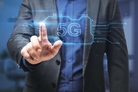 Hand in blurry office pointing at abstract 5G hologram. Communication and speed concept. Double...
