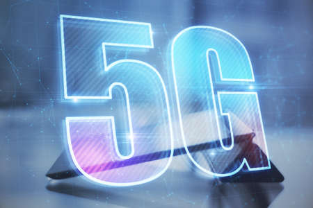 Close up of desktop with tablet and abstract glowing 5G hologram on dark blue background. Wireless infomation and future technology concept. Double exposureの写真素材