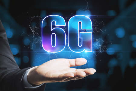 Male hand holding abstract glowing 6G hologram on dark blue background. Internet, technology and communication conceptの写真素材