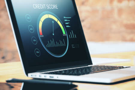 Close up of wooden desktop with laptop computer and abstract credit score scale on screen. Finance and consumer concept