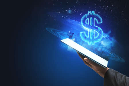 Close up of hand holding tablet with creative glowing polygonal dollar city hologram on blurry blue background with mockup place. Cryptocurrency, online banking, price and trade conceptの写真素材