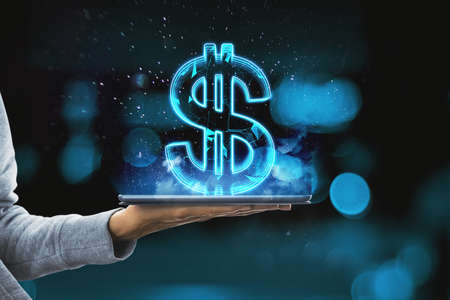 Close up of hand holding tablet with creative glowing polygonal dollar city hologram on blue bokeh background. Cryptocurrency, online banking, price and trade conceptの写真素材