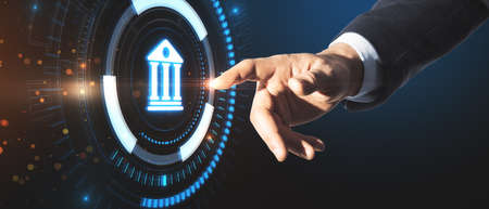 Businessman hand pointing at creative glowing blue public building hologram on dark background. Business, finance and online banking conceptの写真素材