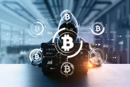 Front view of hacker in blurry interior using computers at desk with creative glowing bitcoin...