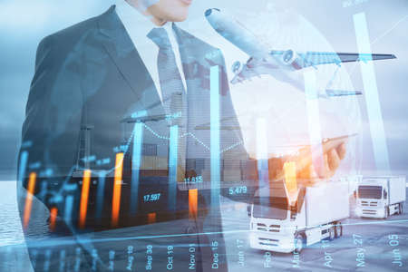 Businessman with smartphone and forex chart standing on abstract double exposure background with cargo airplane, truck and ship. Business, shipping, trade and logistics conceptの写真素材