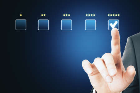Businessman hand choosing 5 stars on abstract glowing rating interface on blue background. Customer...