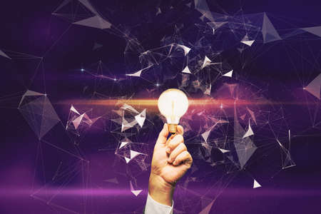 Close up of hand holding glowing polygonal lamp on blurry purple background. Idea and innovation conceptの写真素材