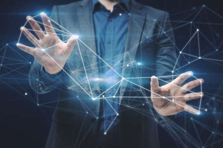 Close up of businessman hand holding abstract polygonal mesh on dark blue background. Innovation and data conceptの写真素材