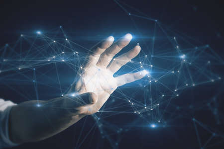Close up of businessman hand holding abstract polygonal mesh on dark blue background. Innovation and...