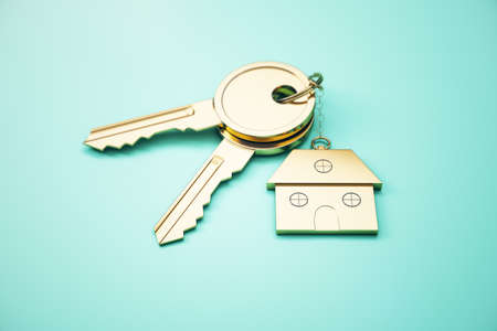 Close up of keys with house keychain on blue surface background. Real estate and property concept. 3D Renderingの写真素材