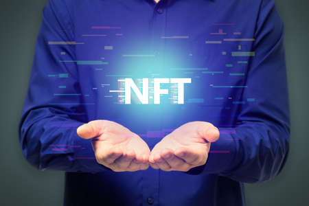Close up of man hands holding creative glowing NFT hologram on dark background. Non-fungible token and cryptocurrency conceptの写真素材