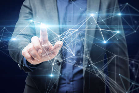 Close up of businessman hand pointing at abstract polygonal mesh on dark blue background. Innovation...