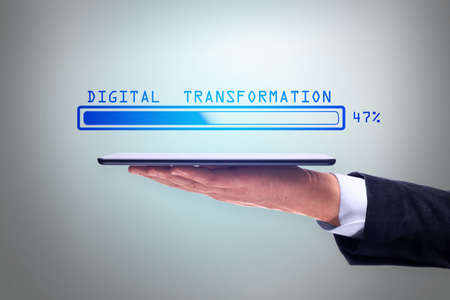 Man hand holding tablet with abstract glowing loading bar on gray wall background. Digital transformation, internet, progress and technology conceptの写真素材
